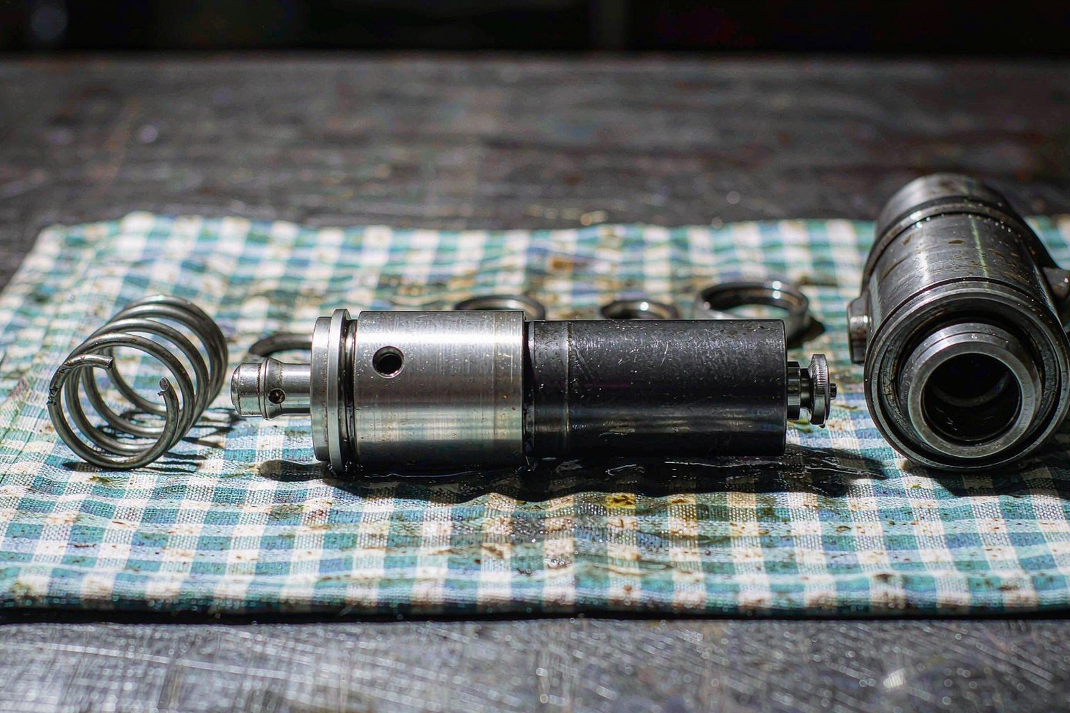 Disassembled hydraulic check valve with stuck poppet and broken spring